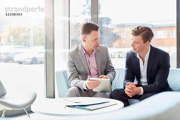 Zwei Geschäftsleute benutzen digitalen Tisch bei Bürobesprechung