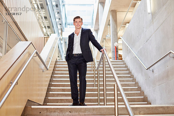 Porträt eines jungen Geschäftsmannes  der auf einer Bürotreppe steht