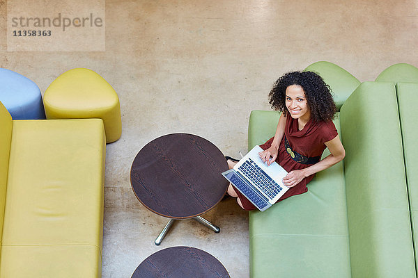 Portrait einer Geschäftsfrau mit Laptop auf einem Design-Studio-Sofa
