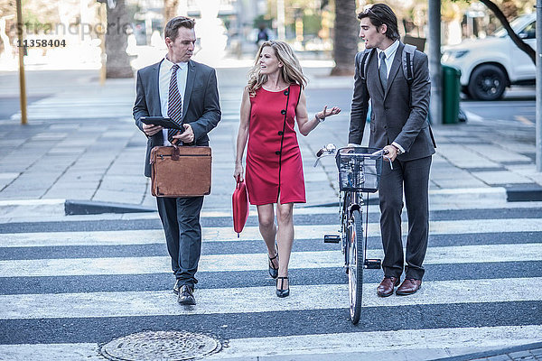 Geschäftsfrau und männliche Kollegen unterhalten sich beim Überqueren der Straße