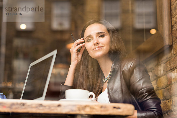 Schaufensterbild einer jungen Geschäftsfrau mit Laptop im Café