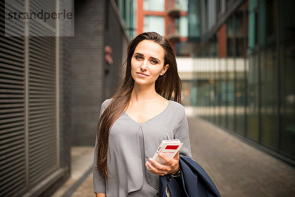 Junge Geschäftsfrau mit Smartphone außerhalb des Büros  London  UK