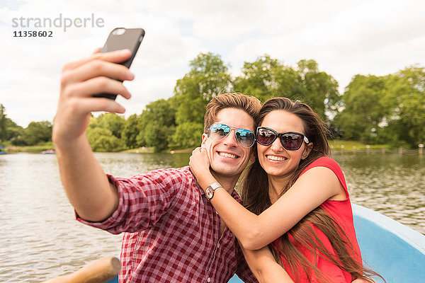 Junges Paar mit Smartphone Selfie im Ruderboot im Regents Park  London  UK