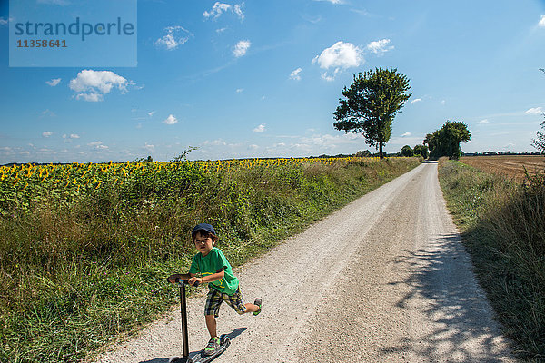 Junge rast auf einem Roller über eine Landstraße  Frankreich