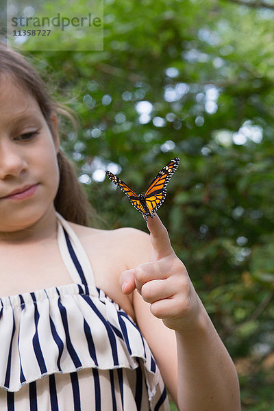 Mädchen hält Monarch-Schmetterling am Finger