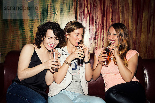 Drei erwachsene Freundinnen trinken in einer Bar