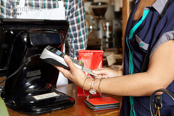Kunde in Bäckerei beim Bezahlen von Waren  mit Kartenautomat  Mittelteil