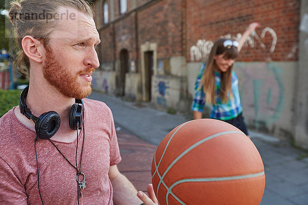 Junges Paar im Freien  Basketball werfend