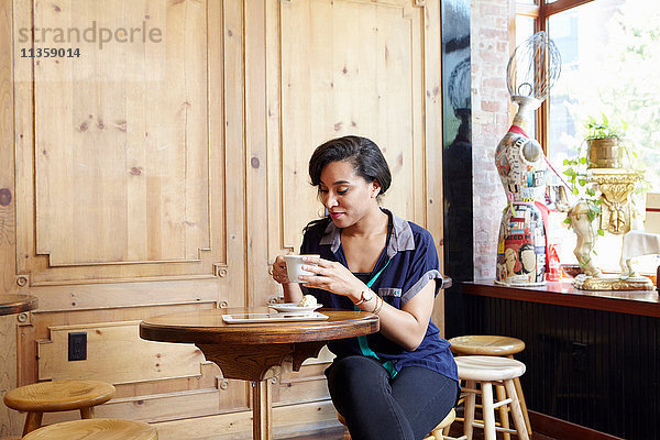 Junge Frau sitzt im Café und trinkt Kaffee