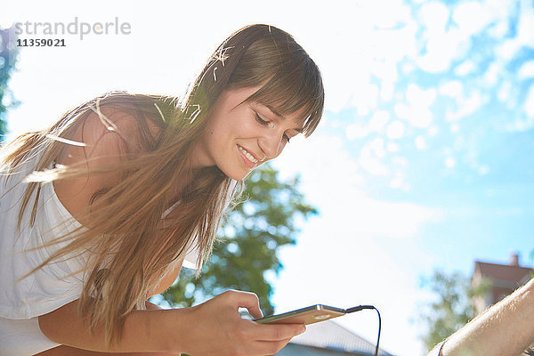 Junge Frau im Freien  benutzt Smartphone  lächelt