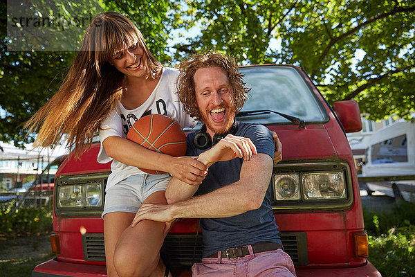 Junges Paar albert im Freien herum  lachend  junge Frau hält Basketball
