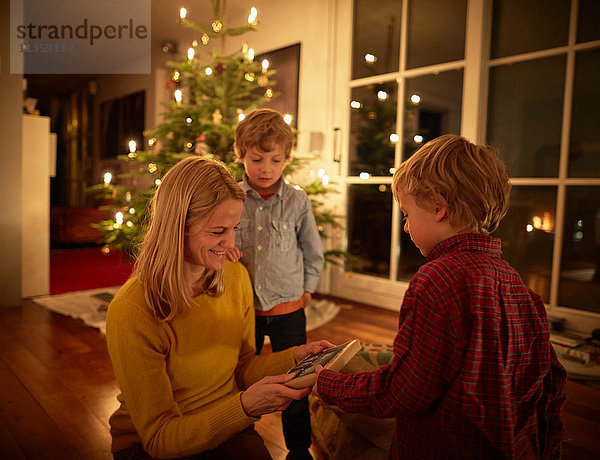 Mutter und Söhne sitzen zu Weihnachten zu Hause und tauschen Geschenke aus