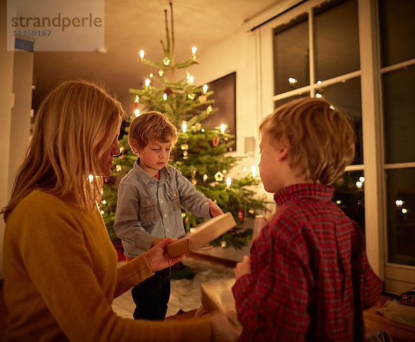 Mutter und Söhne sitzen zu Weihnachten zu Hause und tauschen Geschenke aus