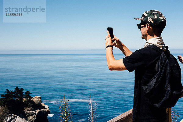 Mann fotografiert Meereslandschaft auf Smartphone  Big Sur  Kalifornien  USA