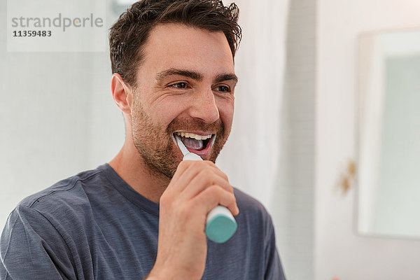 Mann putzt lächelnd die Zähne
