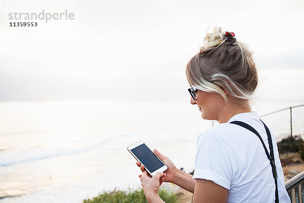 Frau am Meer mit Smartphone in der Hand  Encinitas  Kalifornien  USA