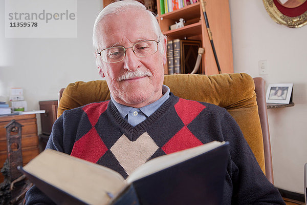 Älterer Mann liest Buch zu Hause