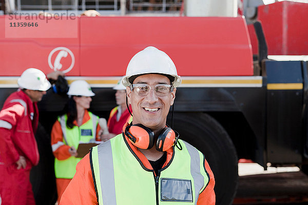 Glücklicher Ingenieur auf der Bohrinsel  Kollegen arbeiten im Hintergrund