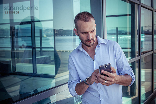 Geschäftsmann schreibt außerhalb des Büros SMS auf Smartphone  Cagliari  Sardinien  Italien