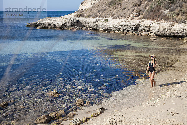 Junge Frau im Badeanzug plaudert am Strand mit einem Smartphone  Villasimius  Sardinien  Italien