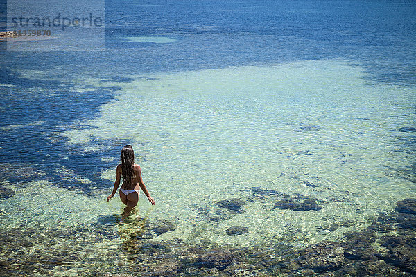 Hochwinkelaufnahme einer jungen Frau  die im Meer paddelt  Villasimius  Sardinien  Italien
