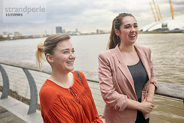 Zwei junge Geschäftsfrauen im Gespräch am Wasser  London  UK