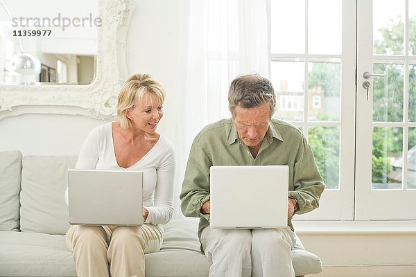 Paar auf Sofa mit Laptops