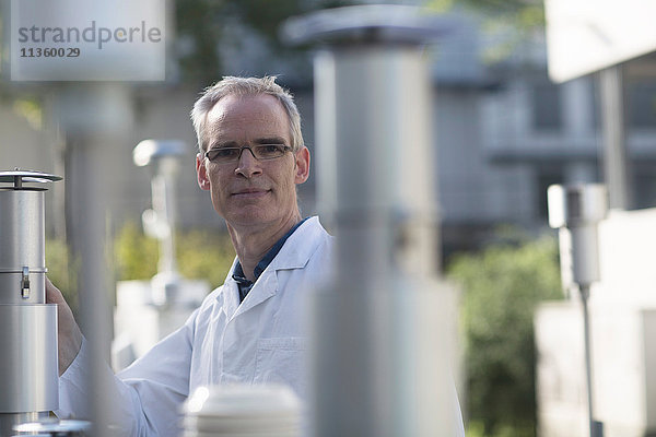 Porträt eines männlichen Meteorologen unter der Ausrüstung einer Wetterstation im Freien