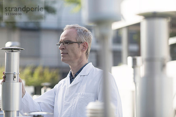 Männlicher Meteorologe  der Messungen der meteorologischen Ausrüstung an der Wetterstation überwacht