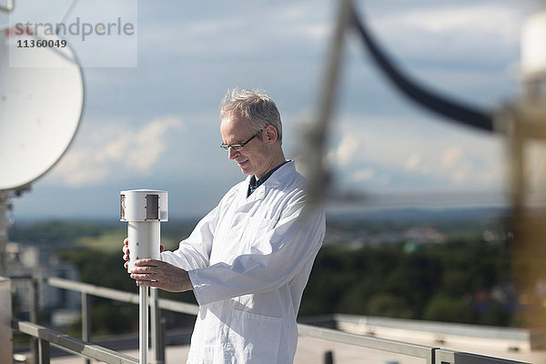 Männlicher Meteorologe überwacht meteorologische Ausrüstung auf der Dachwetterstation