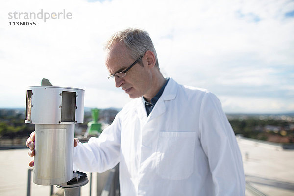 Männlicher Meteorologe überwacht Messungen der meteorologischen Ausrüstung auf der Dachwetterstation