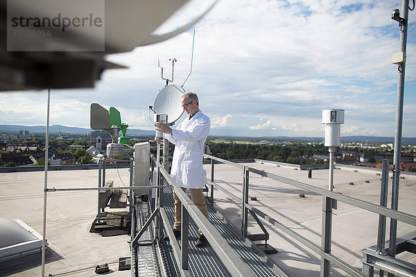 Männlicher Meteorologe aktualisiert Messungen der meteorologischen Ausrüstung auf der Dachwetterstation