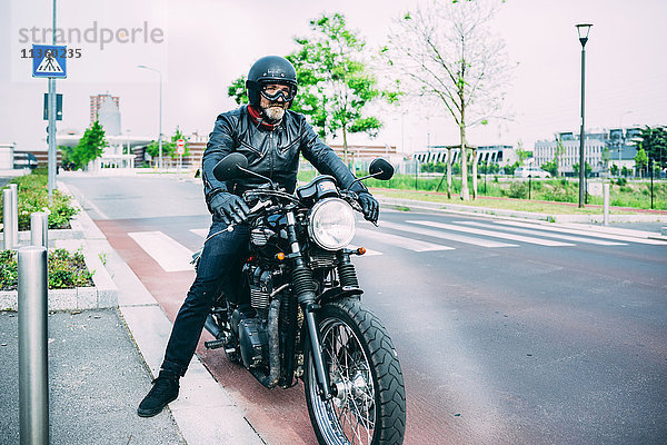 Erwachsener Motorradfahrer sitzt auf dem Motorrad auf der Straße