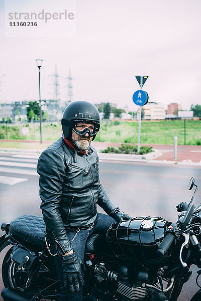 Erwachsener Motorradfahrer sitzt auf dem Motorrad auf der Straße