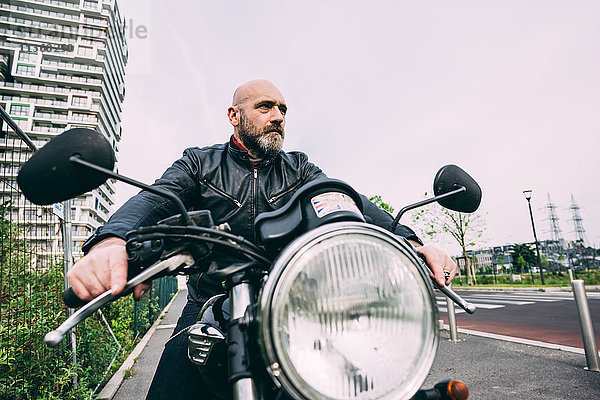 Erwachsener Motorradfahrer sitzt auf dem Motorrad auf der Stadtstraße