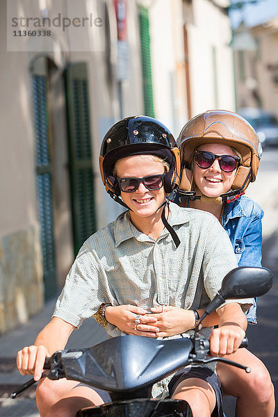 Junges Paar fährt mit dem Moped durchs Dorf  Mallorca  Spanien
