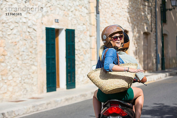 Junge Frau auf dem Sozius durch das Dorf im Rückblick  Mallorca  Spanien