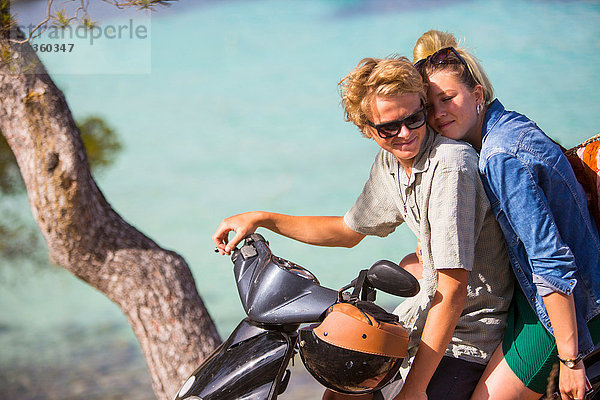 Romantisches junges Paar sitzt auf einem Moped an der Küste  Mallorca  Spanien