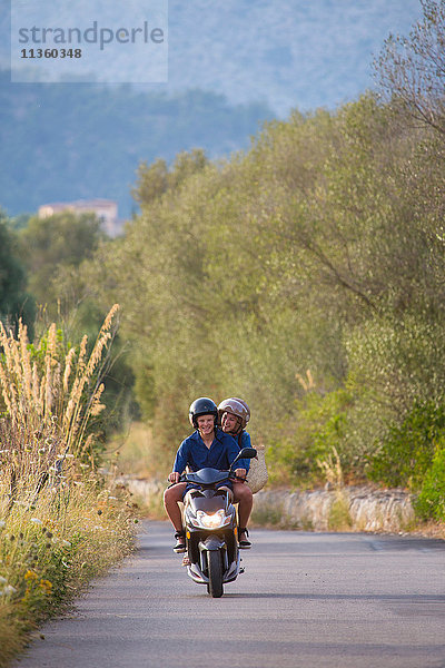 Junges Paar fährt Moped auf einer Landstraße  Mallorca  Spanien