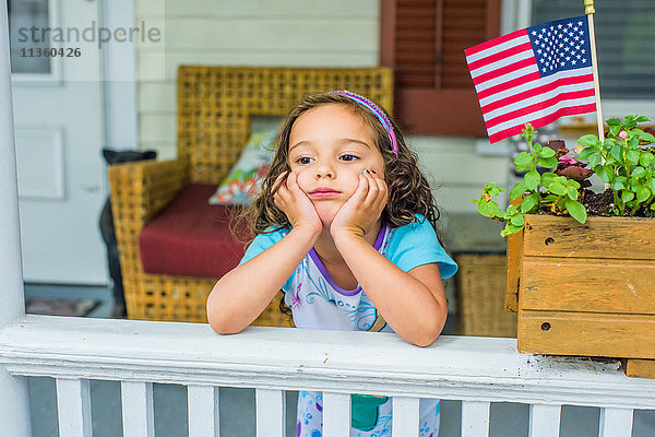 Gelangweiltes Mädchen wartet am Unabhängigkeitstag auf der Veranda