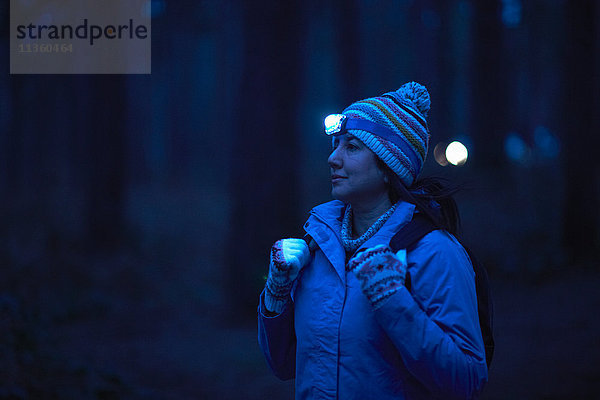 Weibliche Wanderin mit Stirnlampe wandert nachts durch den Wald