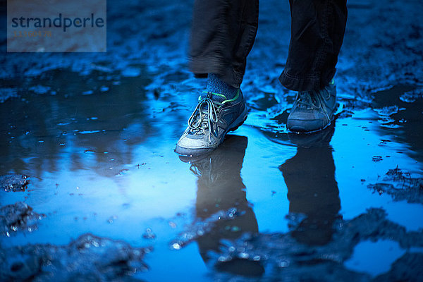 Füße einer Wanderin  die in eine schlammige Pfütze tritt