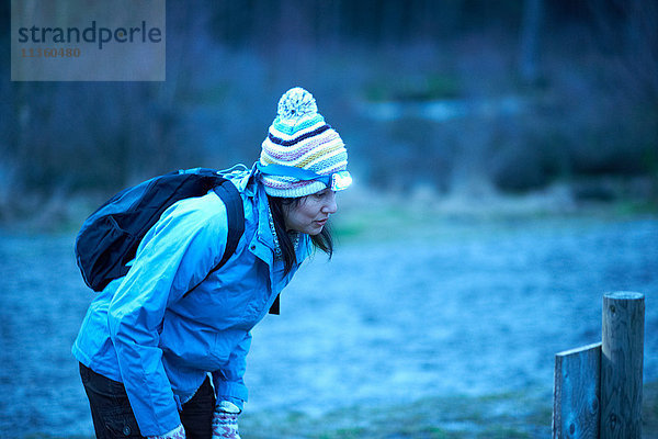 Wanderin mit Stirnlampe liest in der Dämmerung im Wald