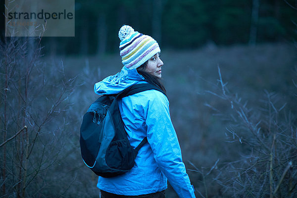 Wanderin blickt in der Dämmerung beim Wandern im Wald zurück