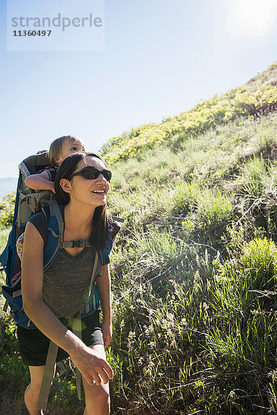 Mutter trägt eine kleine Tochter auf dem Rücken und wandert auf dem Bonneville Shoreline Trail in den Wasatch-Ausläufern oberhalb von Salt Lake City  Utah  USA