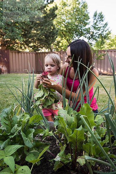 Mutter und kleine Tochter kümmern sich um den Garten