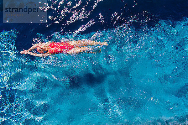 Draufsicht einer Frau  die auf dem Rücken im Schwimmbad schwimmt