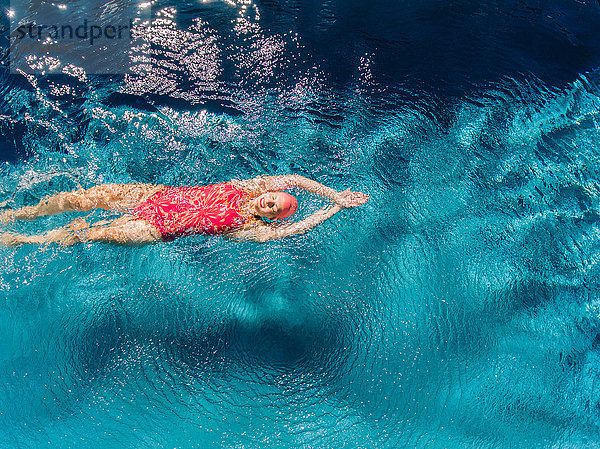 Draufsicht einer Frau  die auf dem Rücken im Schwimmbad schwimmt