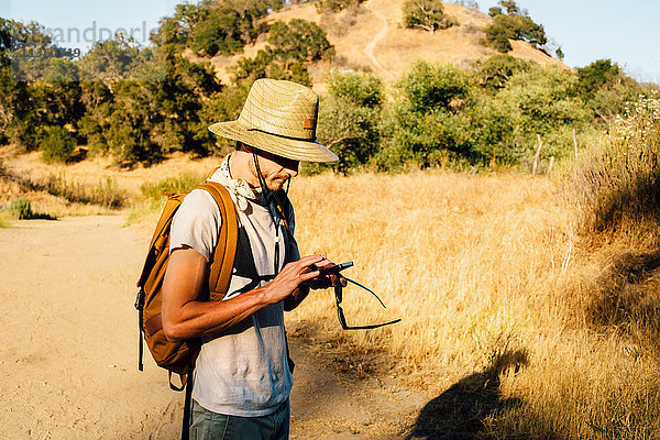 Wanderer schaut auf Smartphone hinunter  Malibu Canyon  Kalifornien  USA