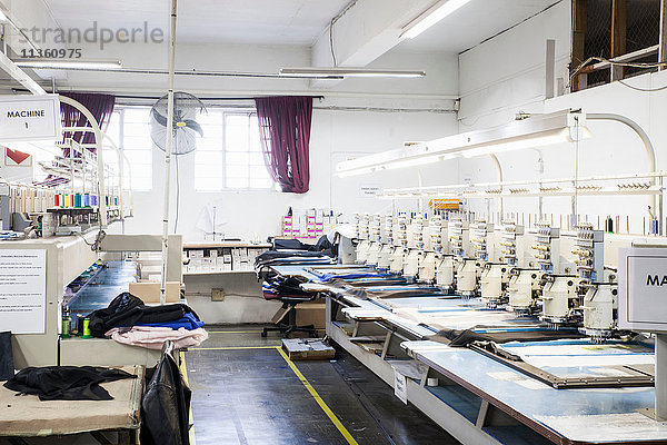 Reihen programmierter Stickmaschinen beschleunigen das Nähen von Stoff in einer Bekleidungsfabrik